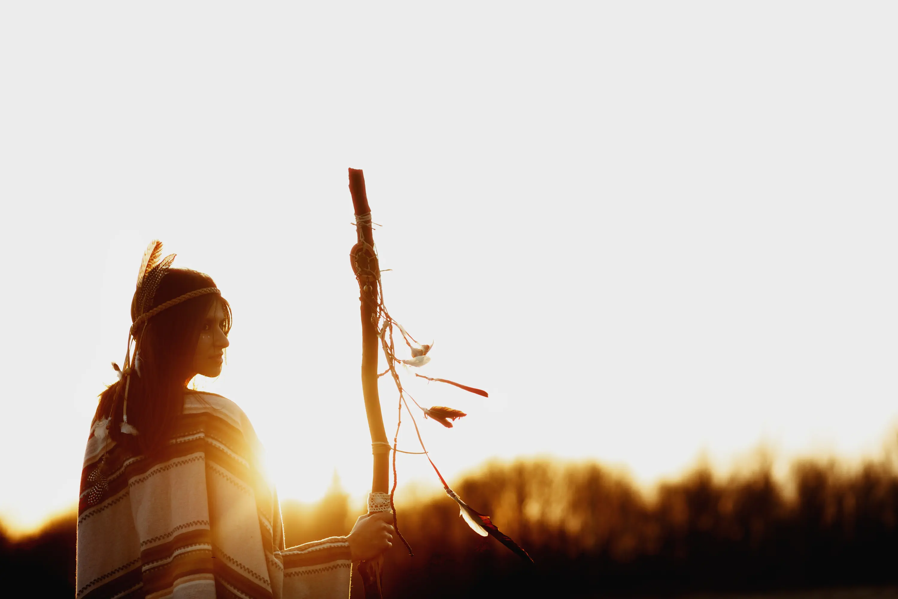 A young indigenous person looking towards a bright horizon.